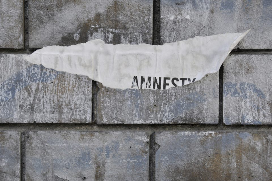 Auf einer Mauer ein abgerissenes Papier mit der Aufschrift Amnesty, Foto von Ieva Jansone